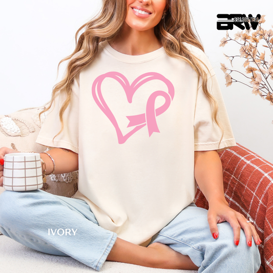 Woman wearing a white t-shirt with a pink heart and bow design, sitting on a couch.