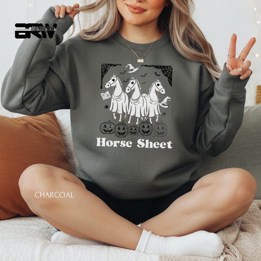 Person wearing a charcoal gray sweatshirt with horse and Halloween design, sitting on a couch.