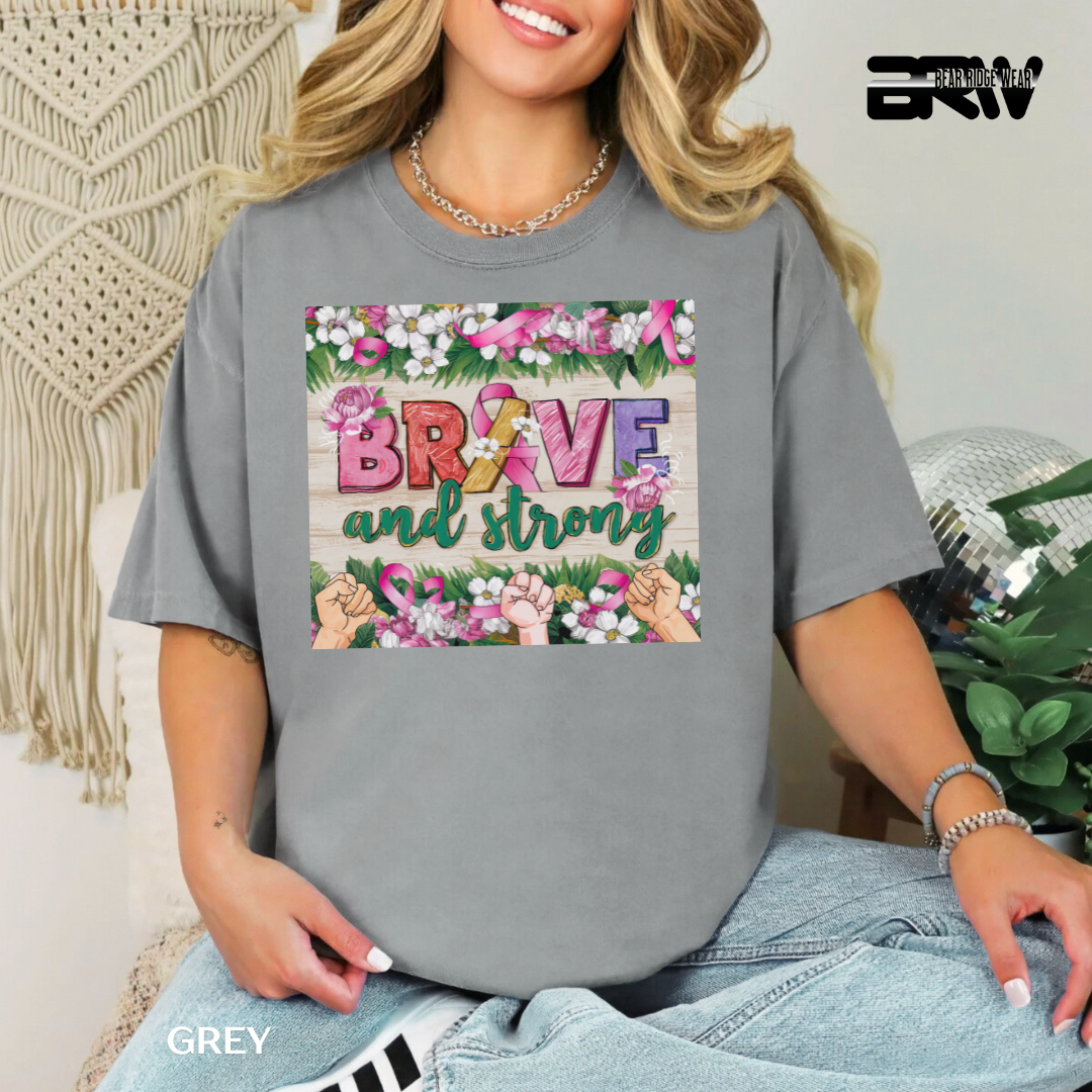 Person wearing a gray t-shirt with 'Be Brave and Strong' design, sitting in a decorative room.