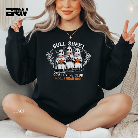 Person wearing a black sweatshirt with 'Bull Sheet Cow Lovers Club' design, sitting on a couch.