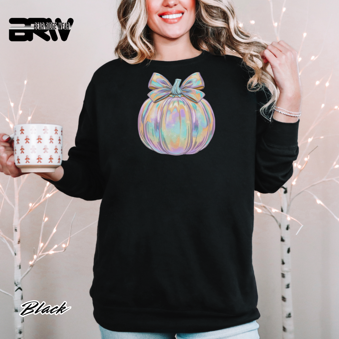 Person wearing a black sweatshirt with a colorful pumpkin design, holding a mug with a white background.