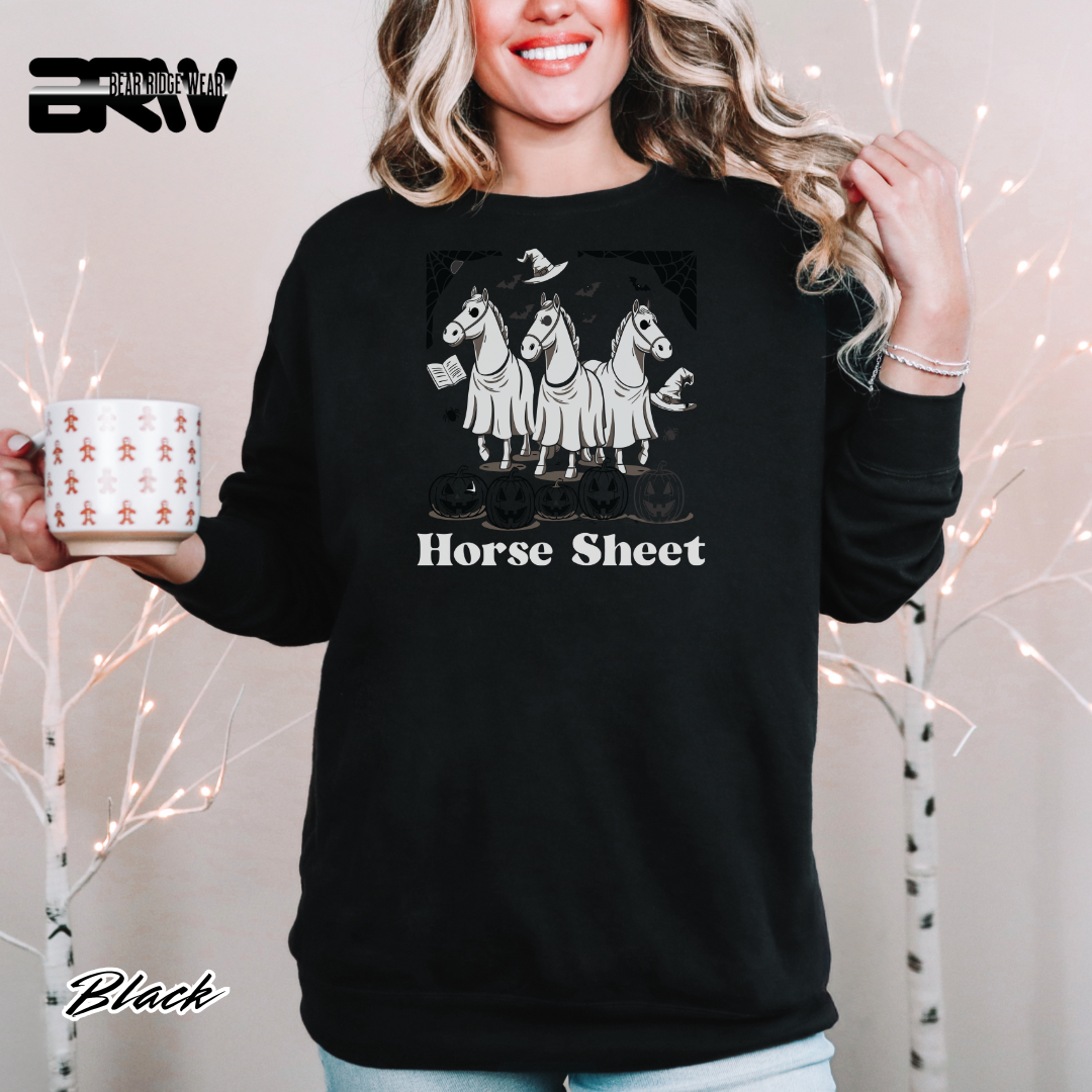 Person wearing a black sweatshirt with horse design and text, holding a mug with decorative design.