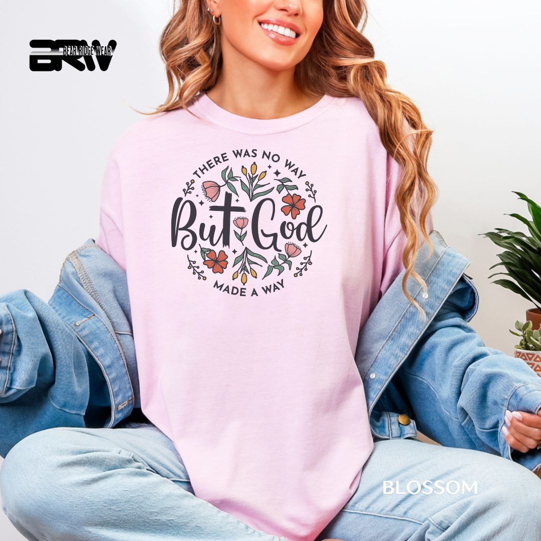 Person wearing a pink sweatshirt with a motivational quote, sitting on a couch. THERE WAS NO WAY BUT GOD MADE A WAY FAITH TEE