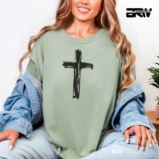 Woman wearing a green sweatshirt with a black cross design, sitting indoors.