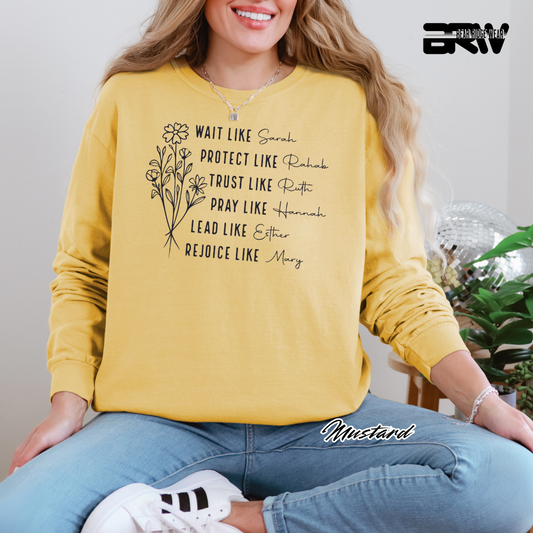 Person wearing a yellow sweatshirt with text and floral design, sitting indoors.