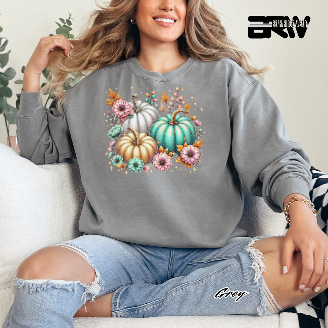Person wearing a gray sweatshirt with pumpkins and flowers design, sitting on a white couch.