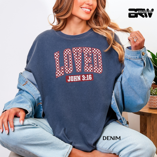 Person wearing a navy sweatshirt with 'LOVED John 3:16' text, sitting indoors.