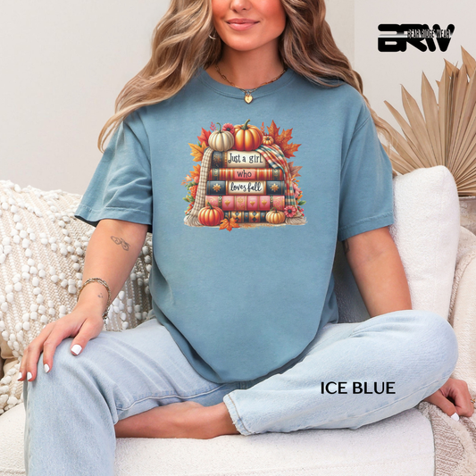 Woman wearing an ice blue t-shirt with a fall-themed design, sitting on a white couch.