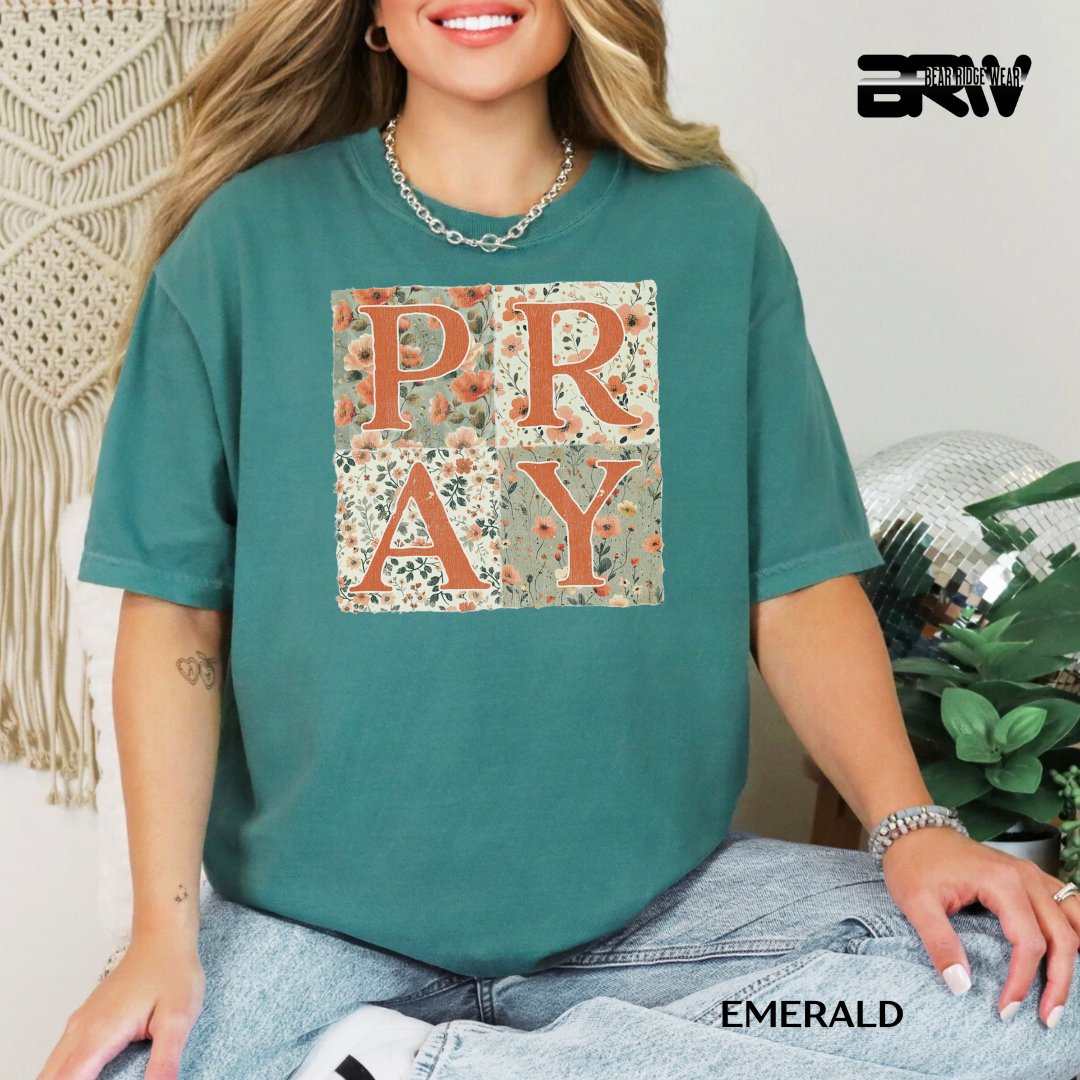 Person wearing a teal t-shirt with 'PRAY' printed on it, sitting indoors.