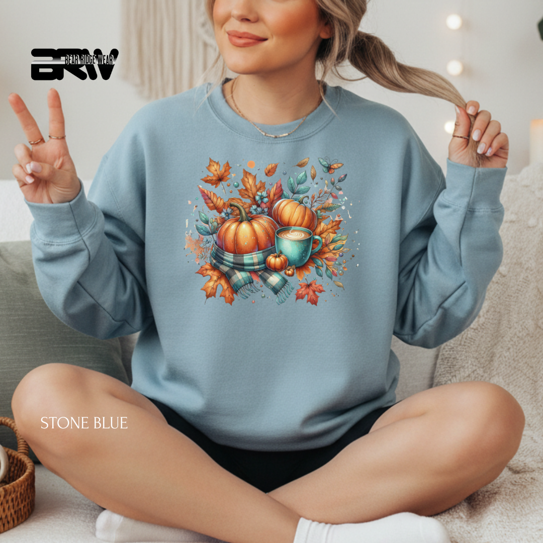 Person wearing a stone blue sweatshirt with autumn-themed design, sitting on a couch.