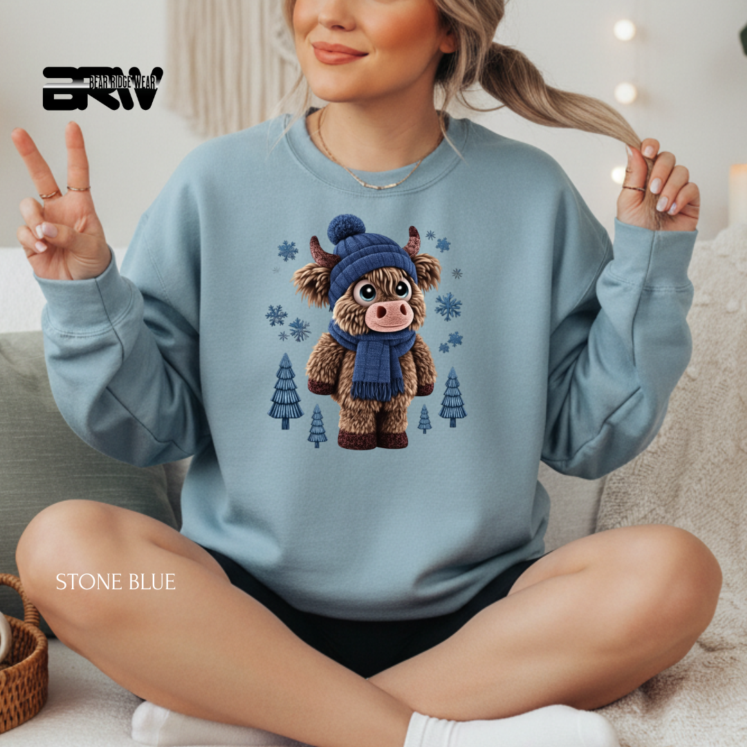 Person wearing a light blue sweatshirt with a cartoon cow design, sitting on a couch.