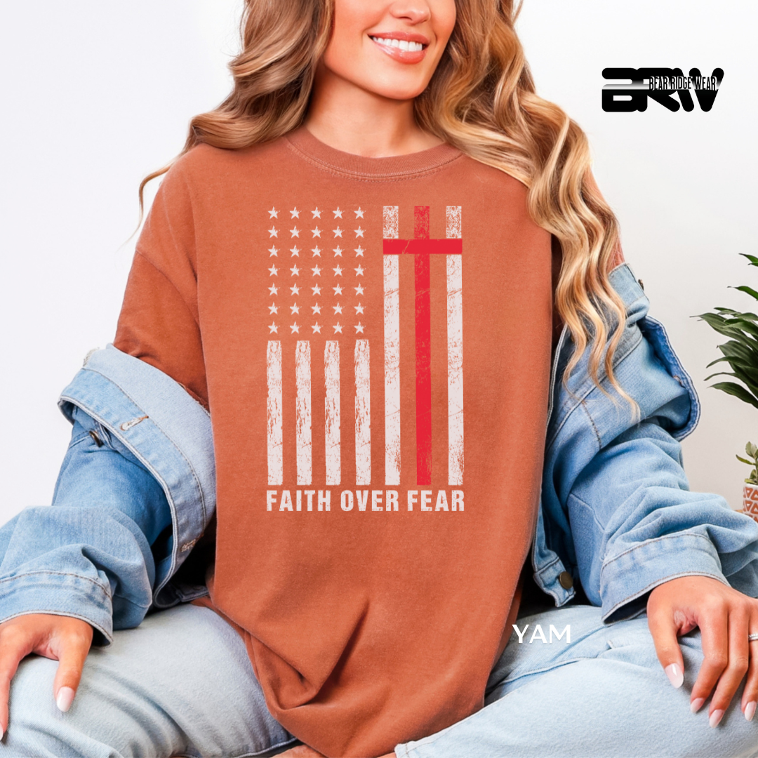 Person wearing a brown sweatshirt with 'Faith Over Fear' design and denim jacket.