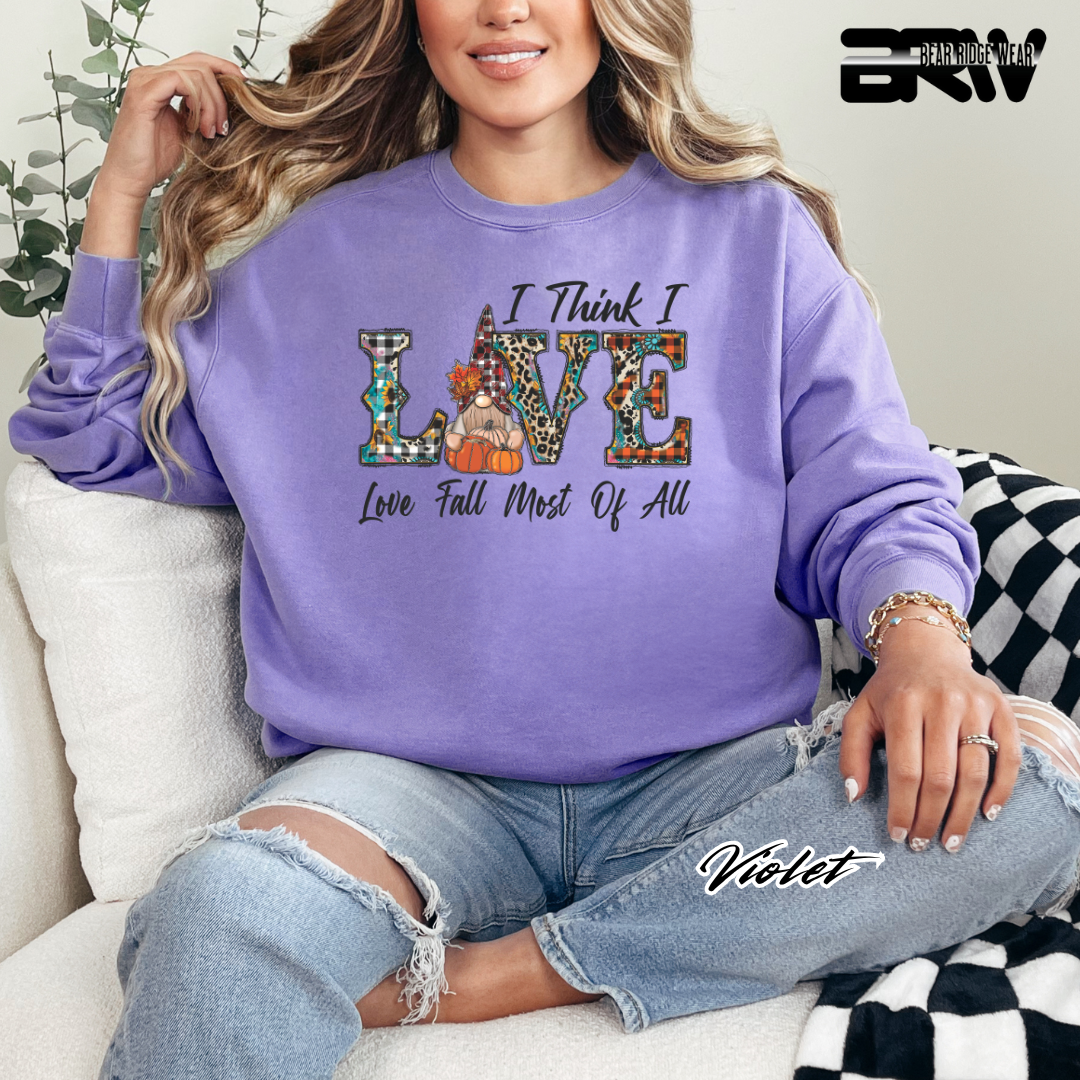 Person wearing a purple sweatshirt with a colorful 'I Think I Love' design, sitting on a couch.