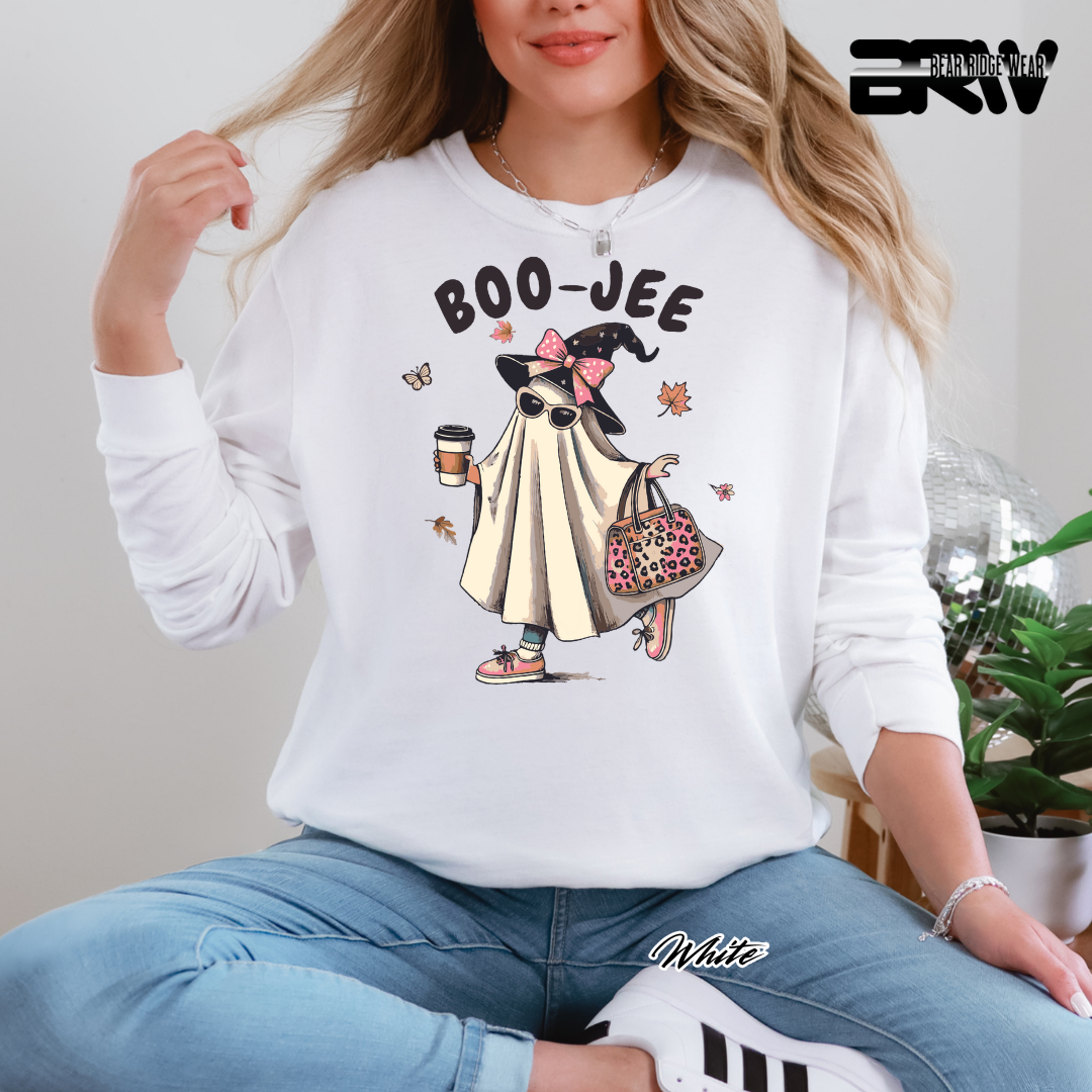 Person wearing a white sweatshirt with a cartoon character and 'BOO-JEE' text, sitting indoors.