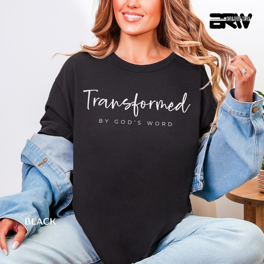 Person wearing a black sweatshirt with 'Transformed by God's Word' text, sitting indoors.