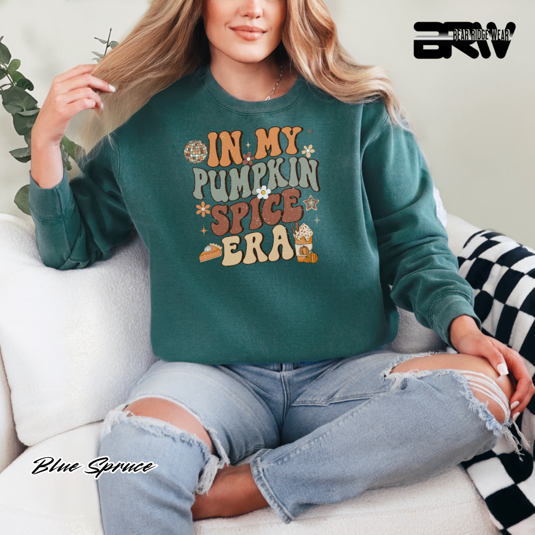 Person wearing a green sweatshirt with 'In My Pumpkin Spice Era' text, sitting on a couch.