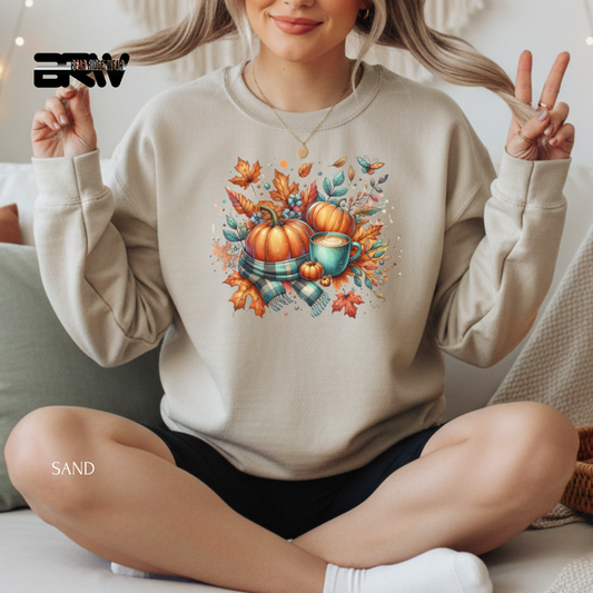 Person wearing a beige sweatshirt with a fall-themed design, sitting on a couch.