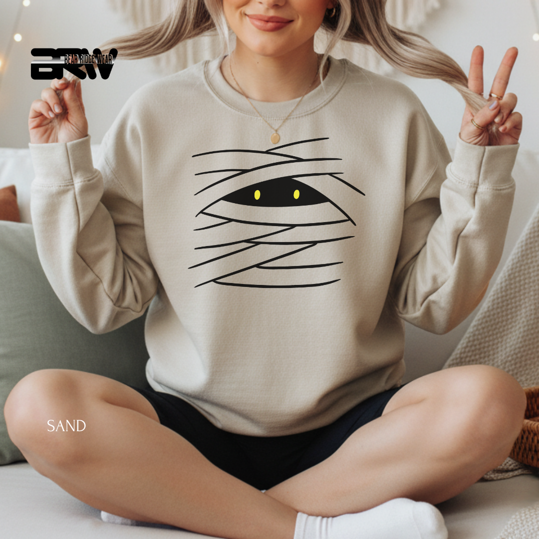 Person wearing a beige sweatshirt with a graphic design, sitting on a couch.