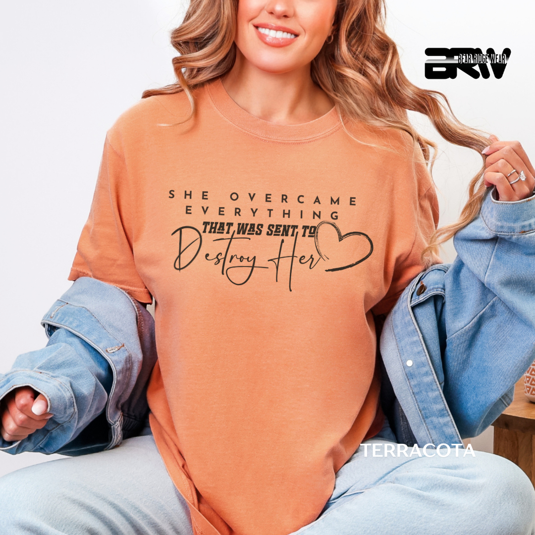 Woman wearing a terracotta-colored sweatshirt with text and a heart design, sitting on a white background.