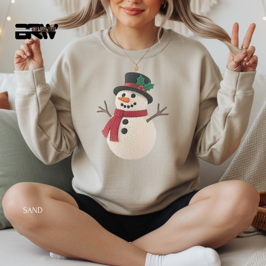 Person wearing a beige sweatshirt with a snowman design, sitting on a couch.