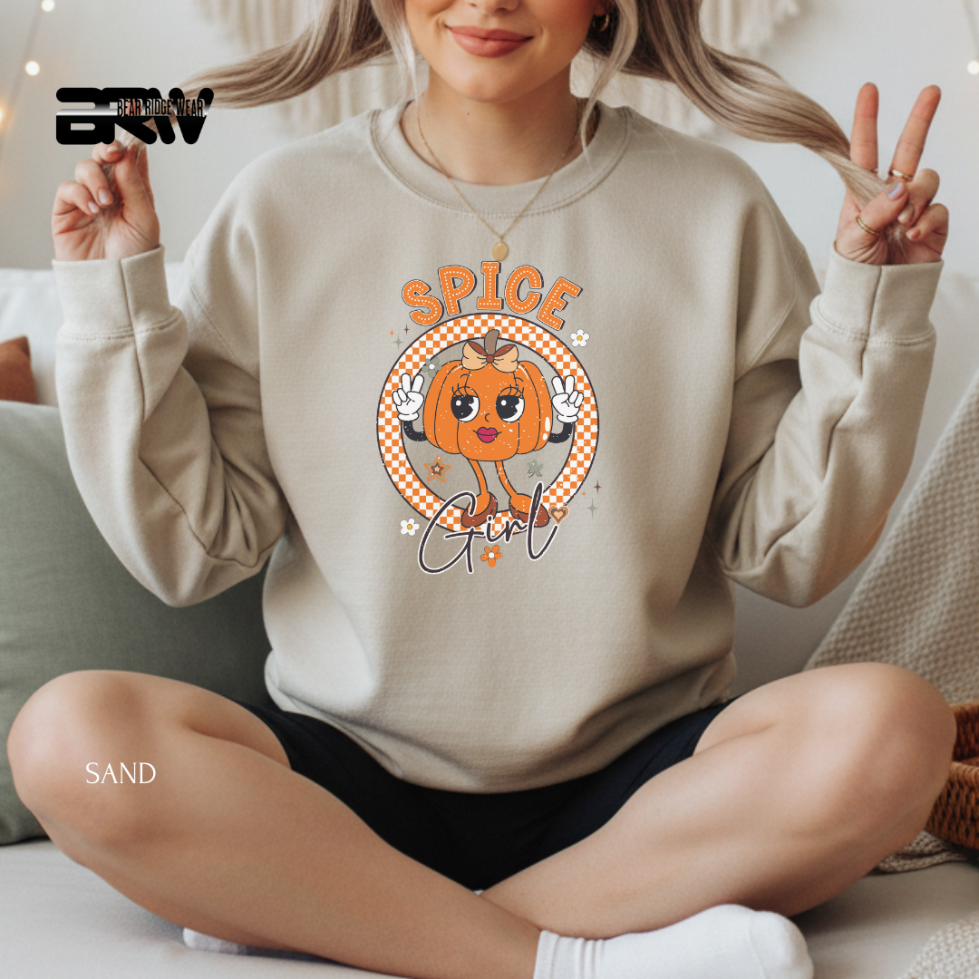 Person wearing a beige sweatshirt with a pumpkin graphic and 'SPICE Girl' text, sitting on a couch.