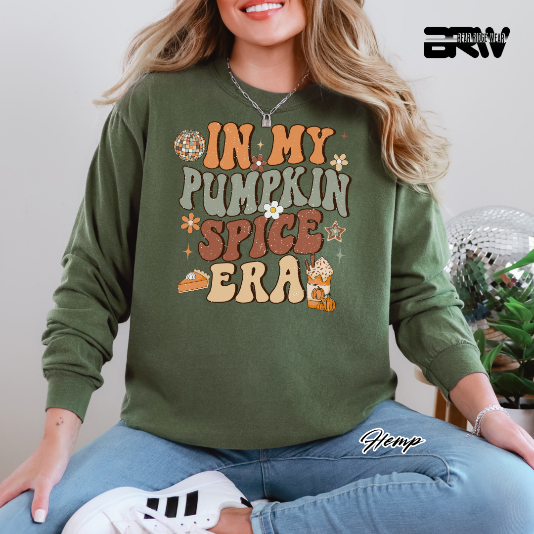 Person wearing a green sweatshirt with 'In My Pumpkin Spice Era' text, sitting indoors.