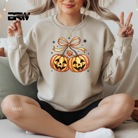 Person wearing a beige sweatshirt with Halloween-themed design, sitting on a couch.
