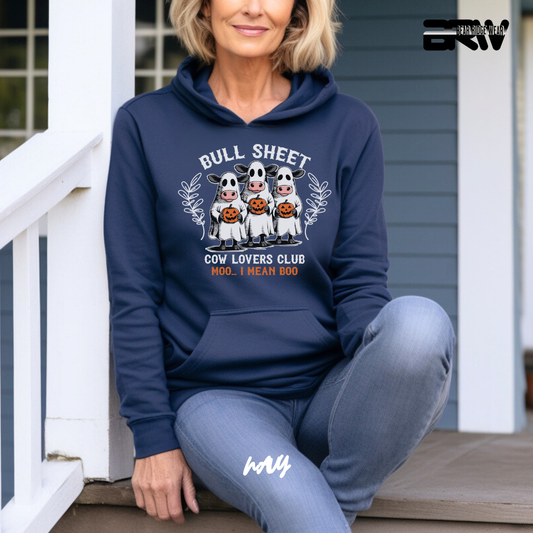 Woman wearing a navy hoodie with 'Bull Sheet Cow Lovers Club' design, sitting on a porch.