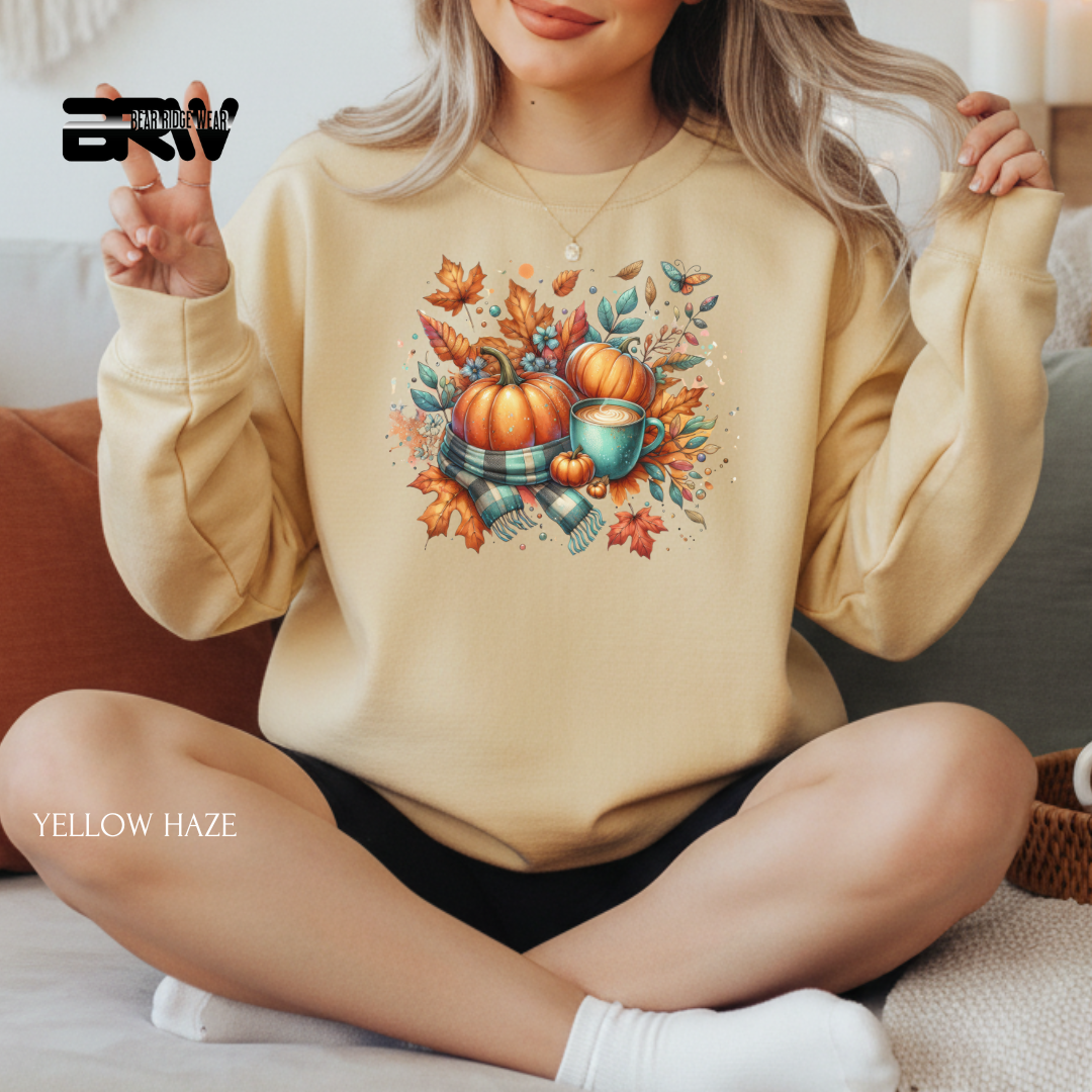 Person wearing a beige sweatshirt with a fall-themed design, sitting on a couch.