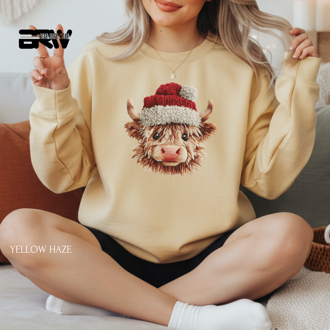 Person wearing a beige sweatshirt with a cow design and Santa hat, sitting on a couch.