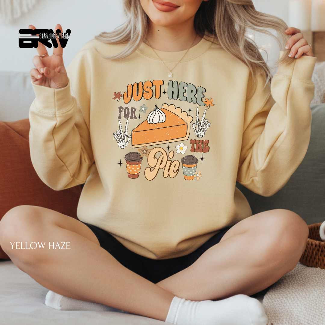 Person wearing a yellow sweatshirt with a pie and coffee design, sitting on a couch.