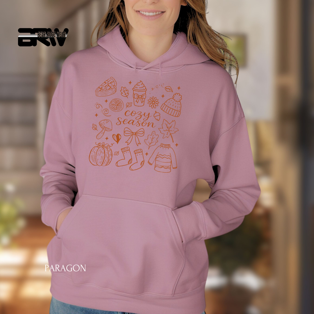 Person wearing a pink hoodie with autumn-themed graphics and text.