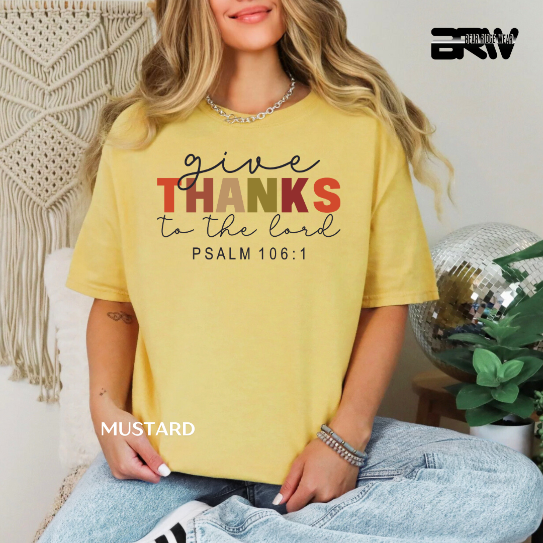 Person wearing a yellow t-shirt with 'give THANKS to the lord' text, sitting in a casual setting.