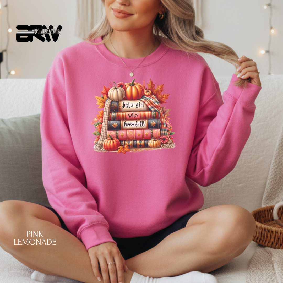 Person wearing a pink sweatshirt with a fall-themed design, sitting on a couch.