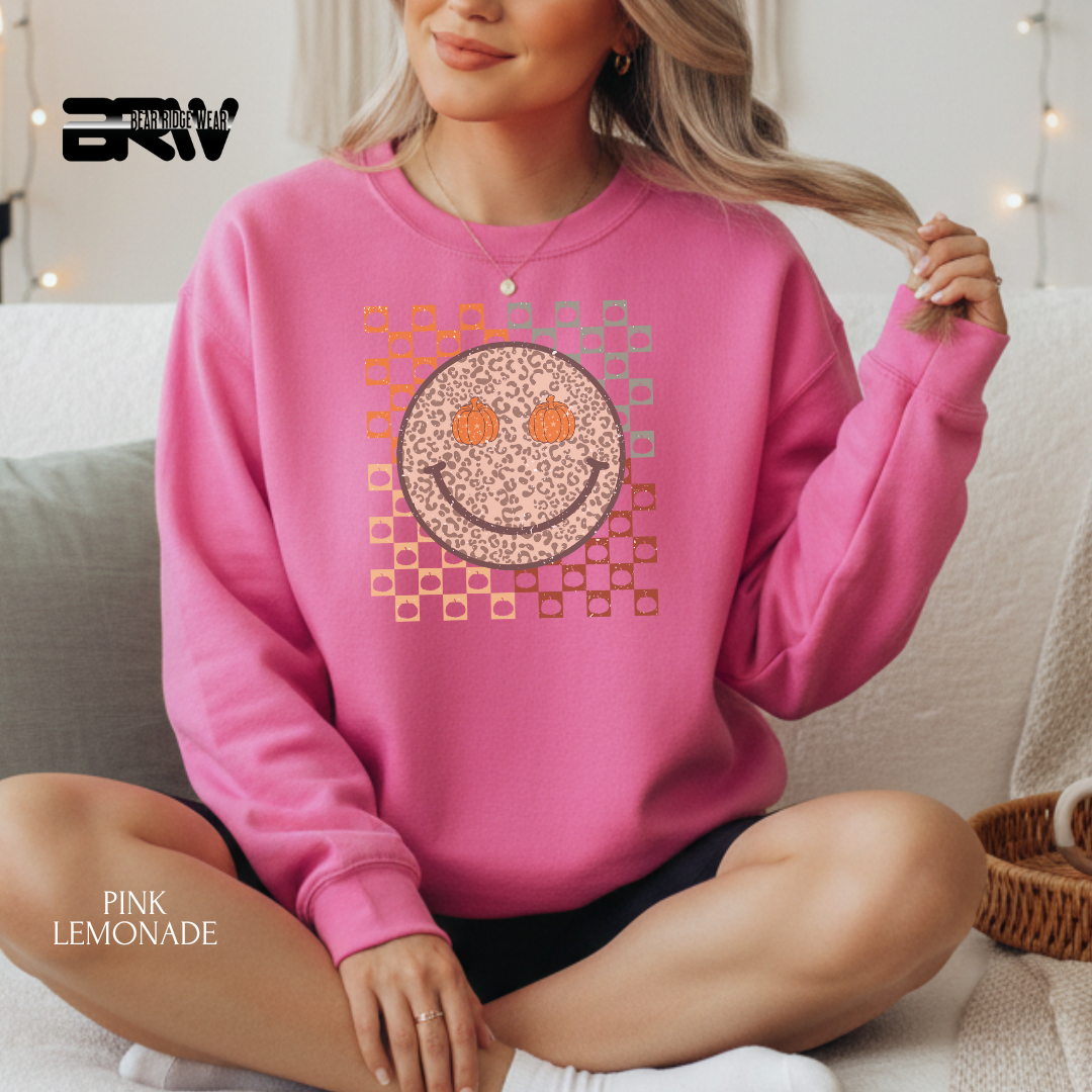 Person wearing a pink sweatshirt with a smiley face design, sitting on a couch.