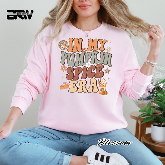 Person wearing a pink sweatshirt with 'In My Pumpkin Spice Era' text, sitting indoors.