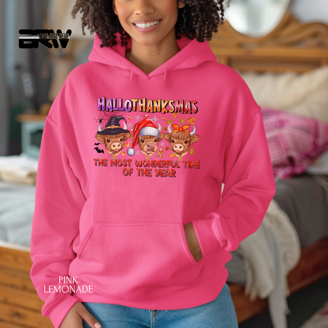 Person wearing a pink hoodie with 'Hallothanksmas' design in a casual setting.