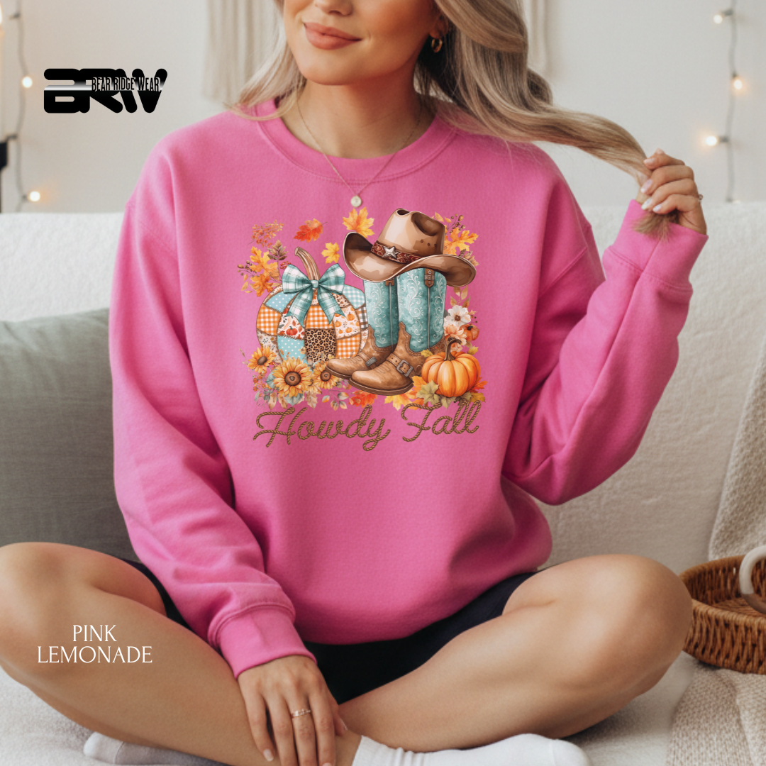 Person wearing a pink sweatshirt with 'Howdy Fall' design, sitting on a couch.