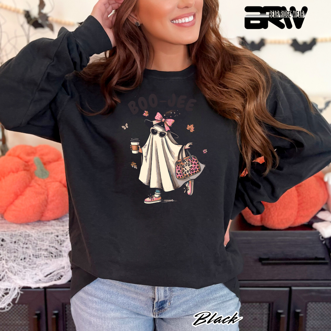 Woman wearing a black sweatshirt with a graphic design, standing in front of pumpkins.