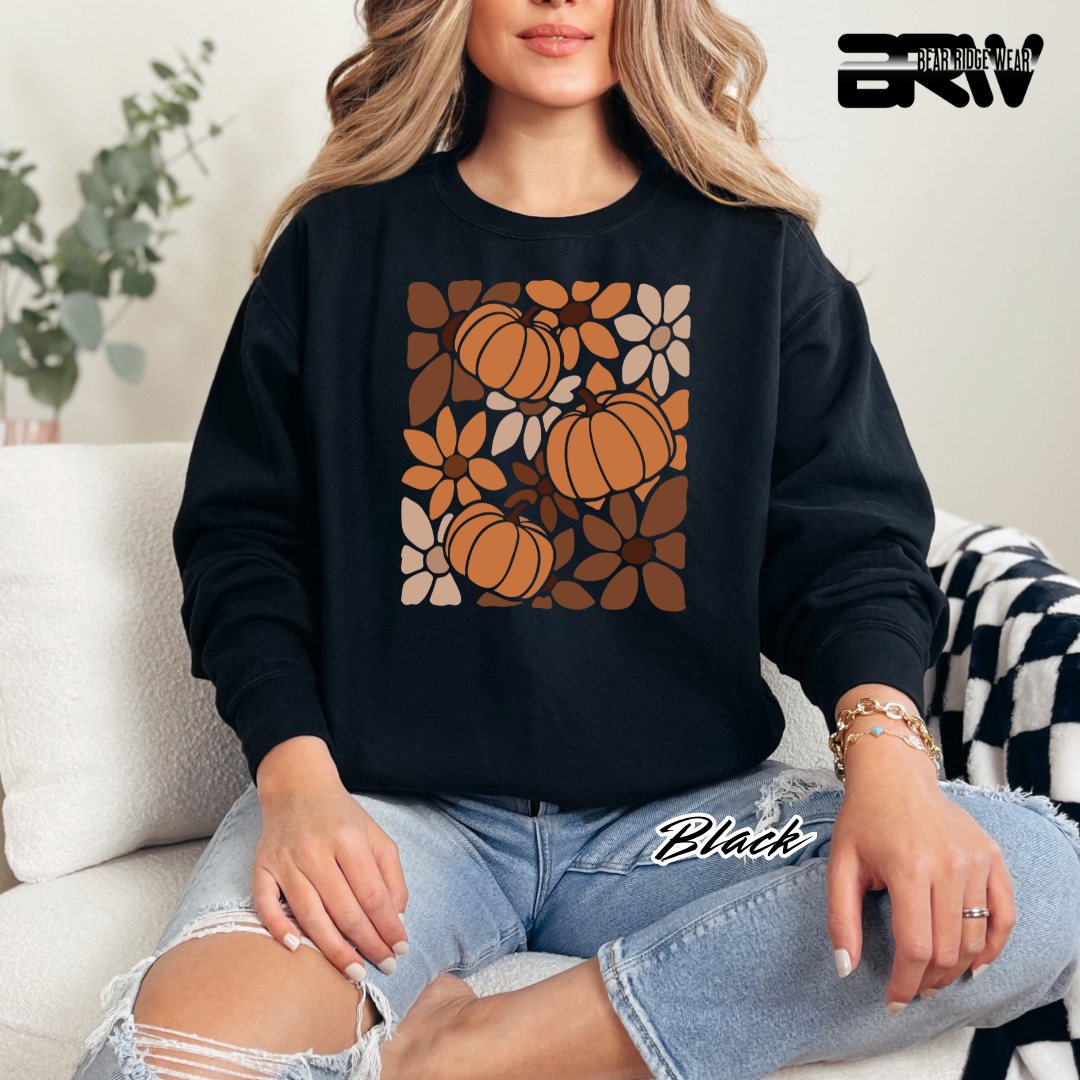 Person wearing a black sweatshirt with pumpkin pattern sitting on a couch.
