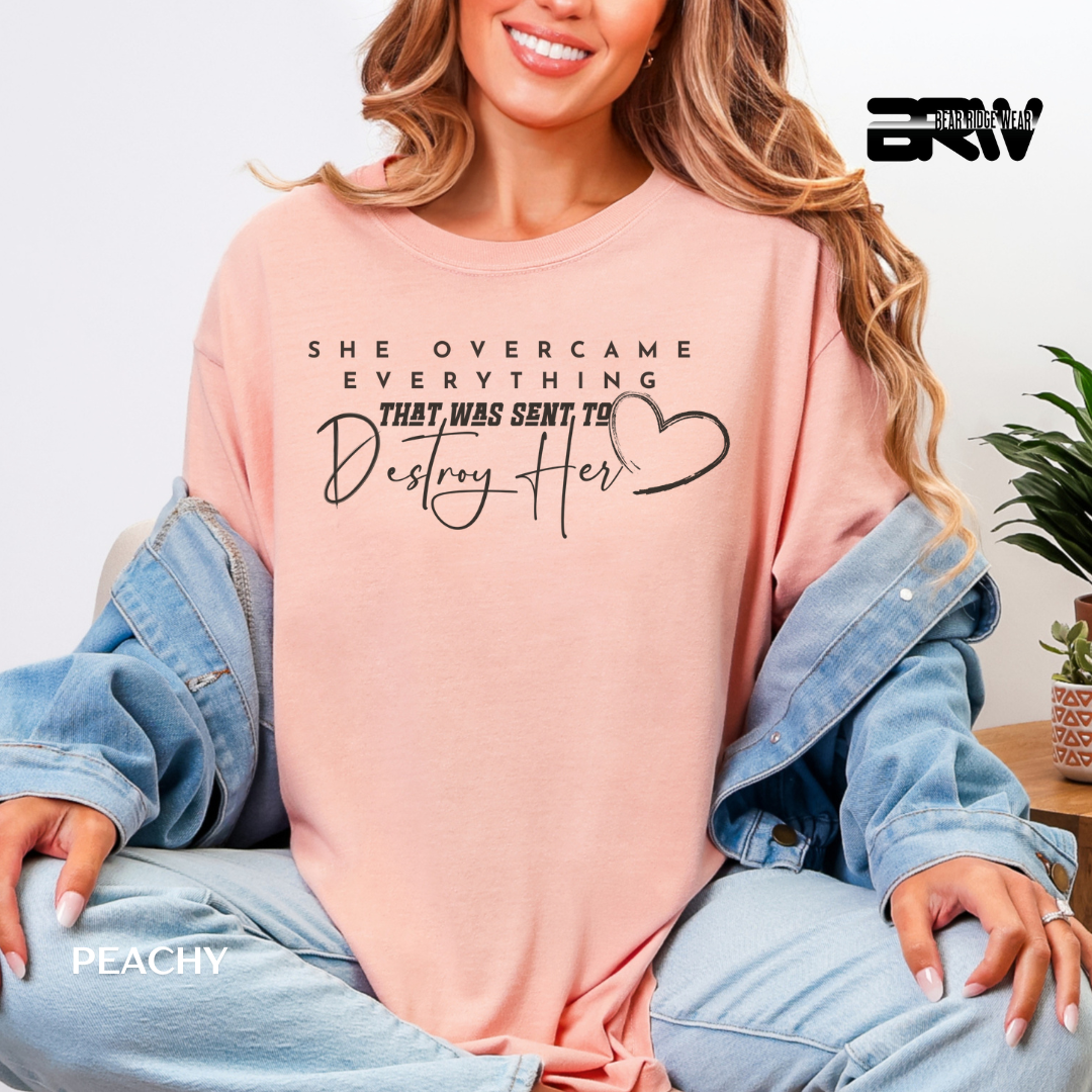 Woman wearing a peach-colored sweatshirt with text and a heart symbol, sitting on a light blue chair.