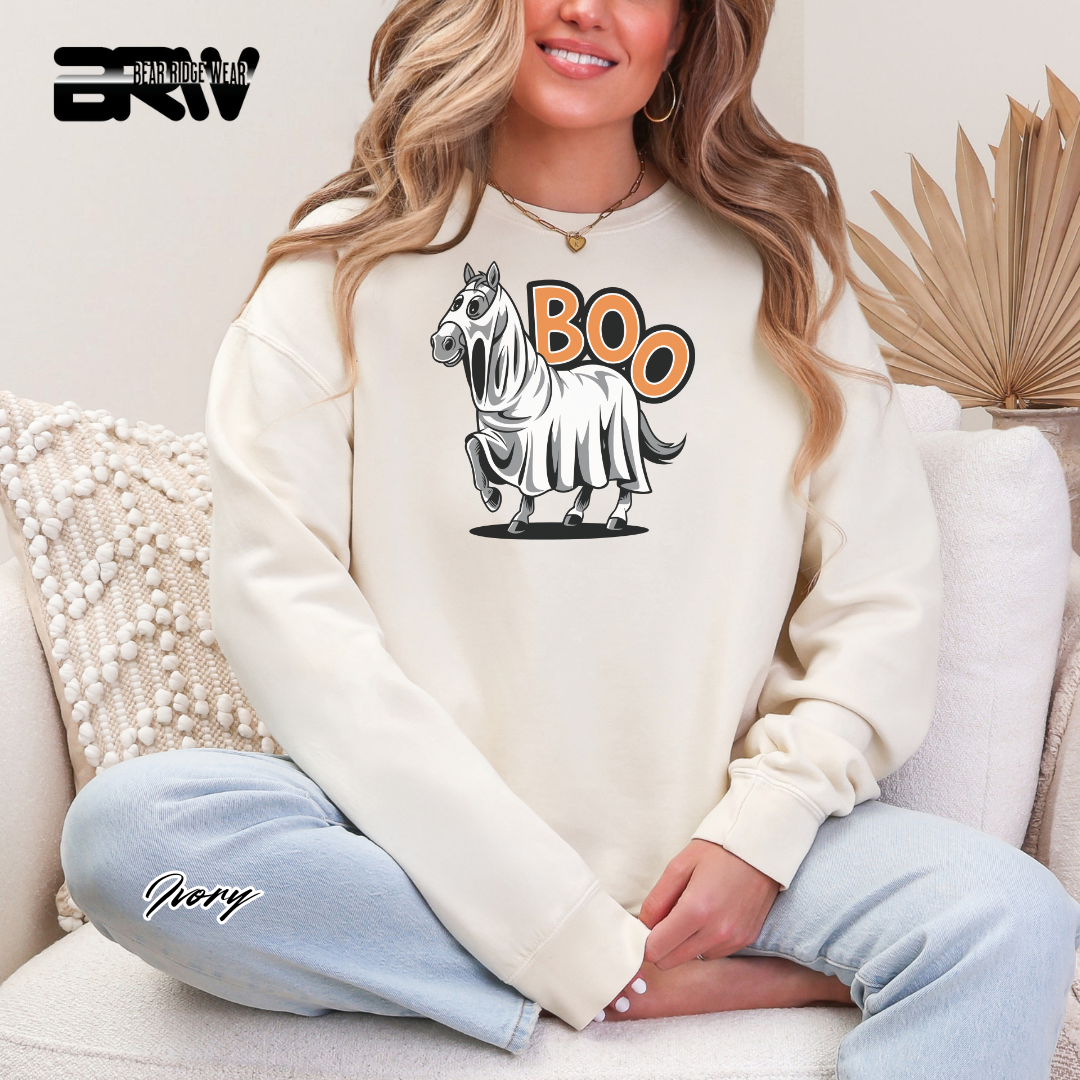 Person wearing a white sweatshirt with a horse graphic and 'BOO' text, sitting on a couch.