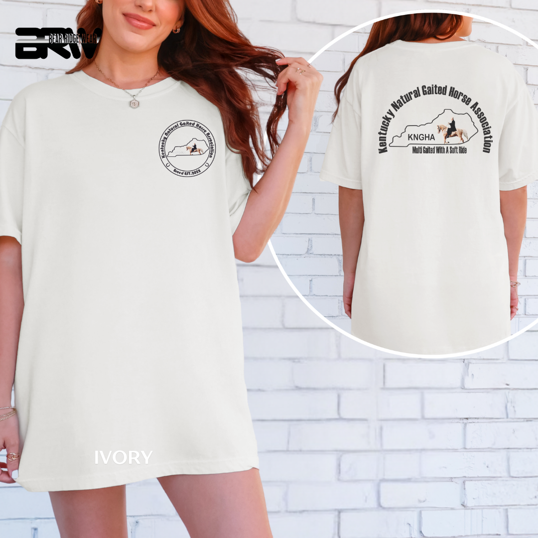 Woman wearing a white t-shirt with a logo and text, against a white brick wall.