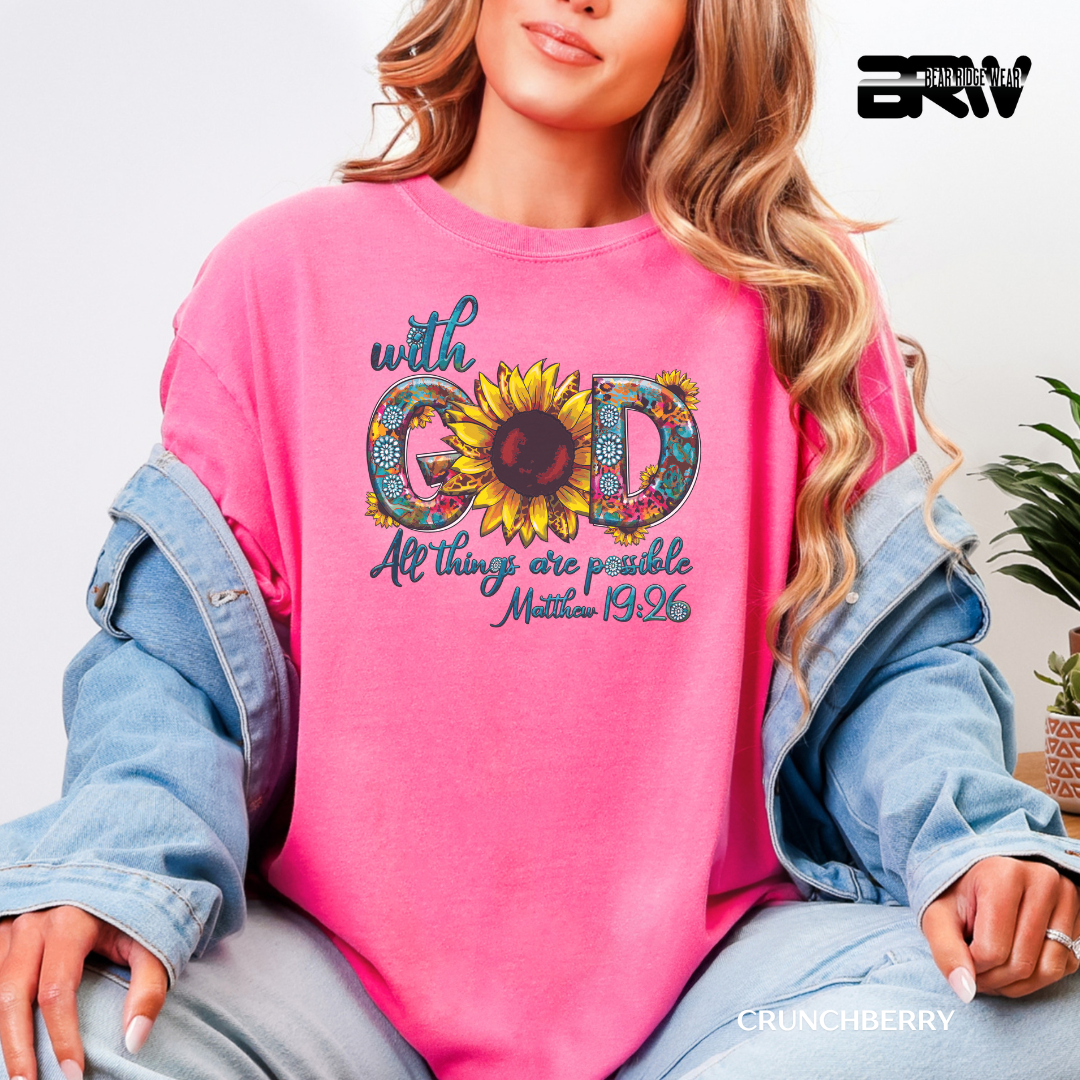 Person wearing a pink sweatshirt with a sunflower design and text, sitting on a couch.