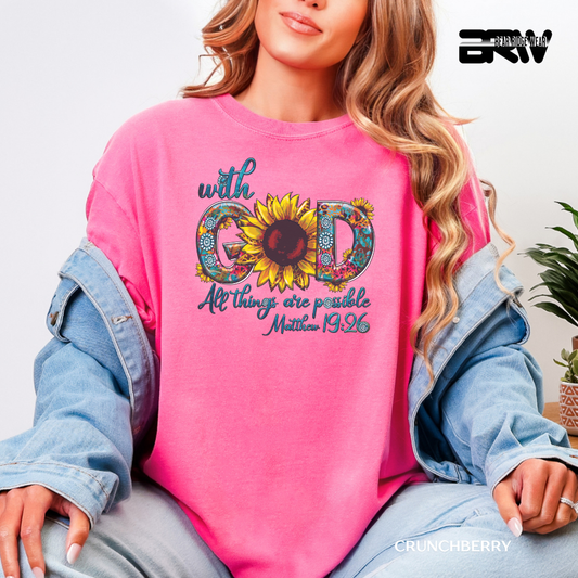 Person wearing a pink sweatshirt with a sunflower design and text, sitting on a couch.