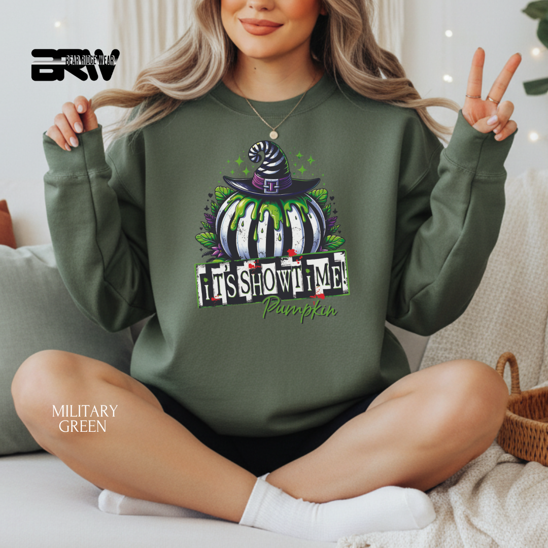 Person wearing a green sweatshirt with a Halloween design, sitting on a couch.