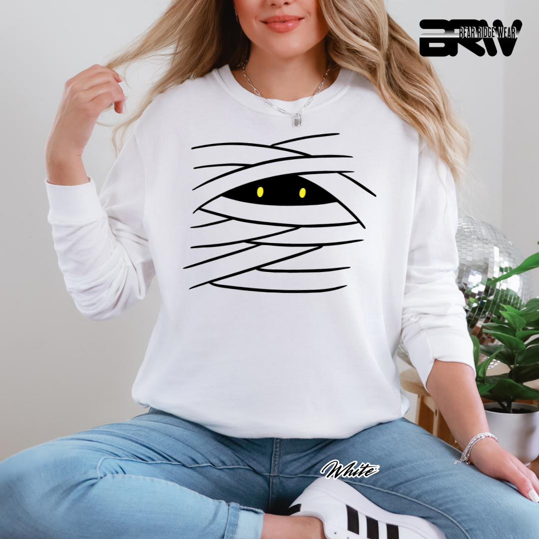 Person wearing a white sweatshirt with a mummy design, sitting indoors.